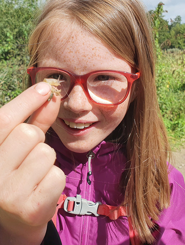 Een dochter van de boswachter houdt een slakje vast
