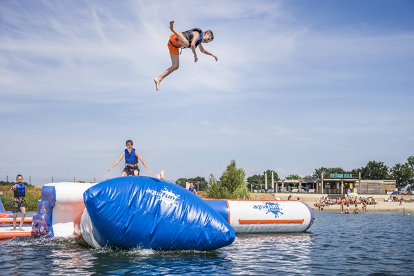 Jongens amuseren zich op het Aquapark in Drakenrijk terwijl er eentje in de lucht vliegt