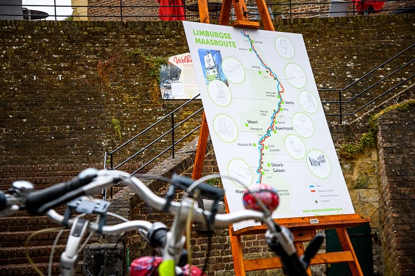 Twee fietsen staan voor een grote kaart van de Fietsroute Maasfietsroute
